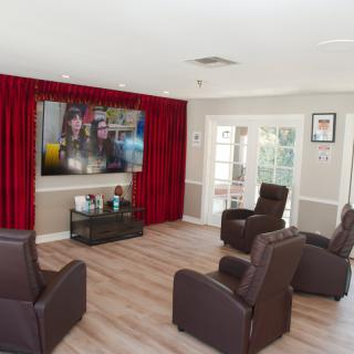 A modern home theater with recliner chairs and a large TV.