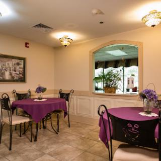 A cozy dining area featuring purple tablecloths and elegant seating arrangements, illuminated by warm lighting.