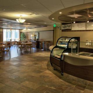 A modern cafe interior with empty seating and a display case at the counter.