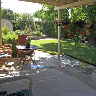 A cozy patio overlooking a lush garden with outdoor furniture and vibrant greenery.