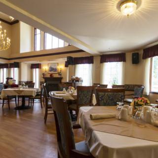 An elegant dining room with neatly arranged tables and chandeliers.