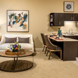 A modern living room with a cozy seating area, abstract artwork, and an adjoining kitchen space.