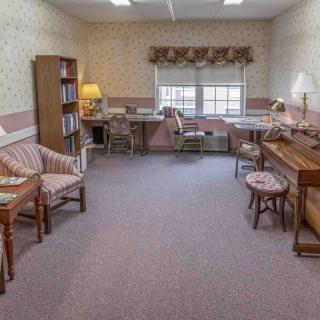 A classic office space with desks, chairs, and a bookshelf set against patterned wallpaper.