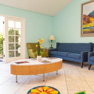 A bright and inviting living room featuring blue sofas, a stylish coffee table, and vibrant artwork.