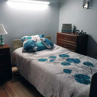 A cozy bedroom with a neatly made bed adorned with floral bedding and surrounded by wooden furniture.