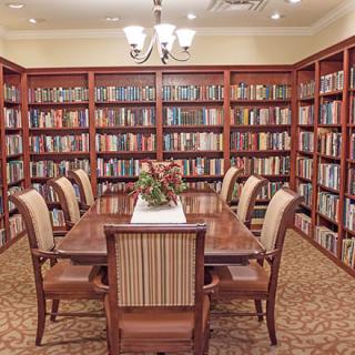 An elegant library with shelves filled with books and a central table surrounded by chairs.