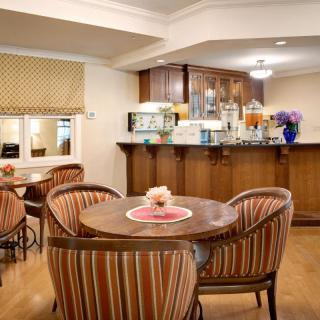 A cozy cafe interior with round tables, cushioned chairs, and a wooden counter.