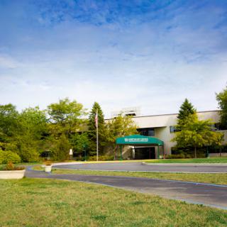 A peaceful view of a building surrounded by greenery under a clear blue sky.