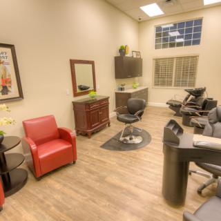 A cozy salon interior with comfortable chairs and a mirror.