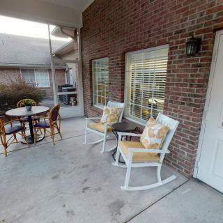 A cozy patio area featuring rocking chairs and a table set against a brick wall.