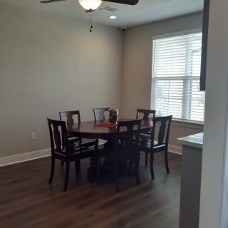 A cozy dining area with a round wooden table and four chairs, featuring natural light from a window with blinds.