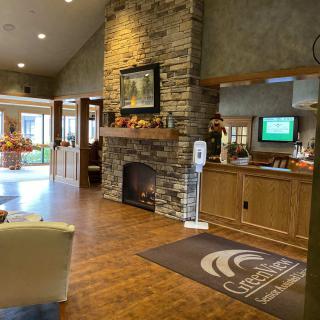 A cozy reception area with a stone fireplace, wood flooring, and a welcoming desk.