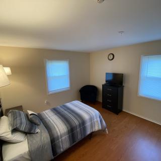A cozy bedroom with a bed, television, and wooden flooring.