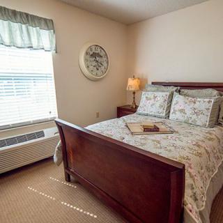 A cozy bedroom with a wooden bed frame, floral bedding, and a bedside lamp.