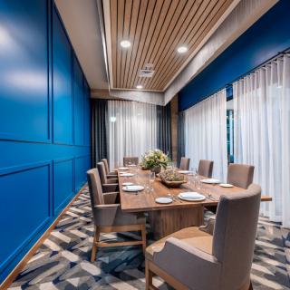 A modern dining room with blue walls, a wooden table, and comfortable chairs.