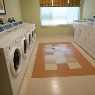 A clean laundry room with multiple washing machines and tiled flooring.