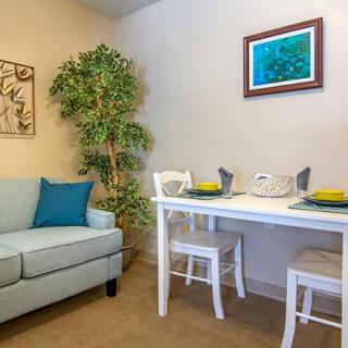 A cozy living room with a sofa and a small dining table set for two.
