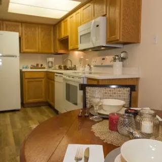 A cozy modern kitchen featuring wood cabinetry, essential appliances, and a welcoming dining area.