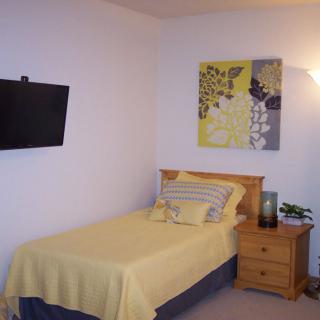 A cozy bedroom with a single bed, wall-mounted television, and decorative wall art.