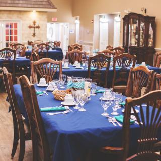 An elegantly set dining area with blue tablecloths and neatly arranged tables and chairs.