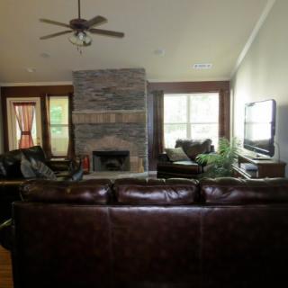 A cozy living room featuring a central fireplace, leather sofas, and a flat-screen TV.