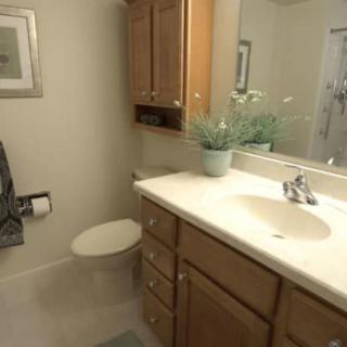 A clean and modern bathroom with a wooden cabinet, a large mirror, and decorative elements.