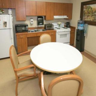 A cozy kitchen area with a round table and chairs, equipped with various appliances and a water cooler.