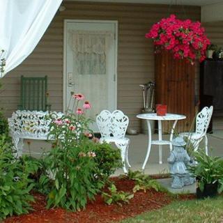 A cozy patio with white garden furniture and vibrant flowers.