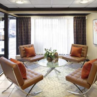 A modern lounge area with stylish chairs and a glass center table, illuminated by natural light.