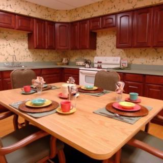 A cozy kitchen with a wooden dining table set for four, featuring colorful plates and cups.