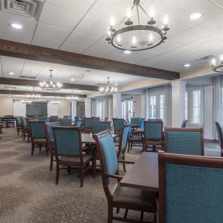A spacious dining area with elegant chandeliers and neatly arranged tables and chairs.
