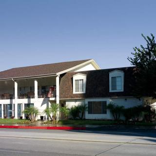 A two-story motel with balconies and a small garden area alongside the street.