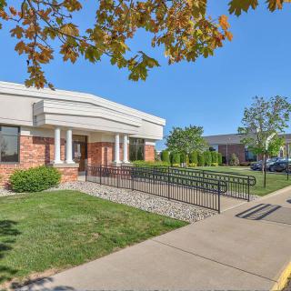 A brick building with an accessible entrance, surrounded by trees and a well-maintained lawn.