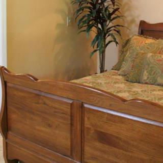 A cozy bedroom featuring a wooden bed and decorative pillows, complemented by a potted plant in the corner.