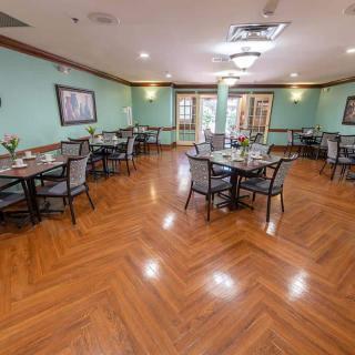 A spacious dining room with neatly arranged tables and chairs on a polished wood floor.