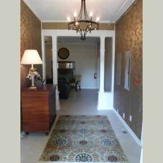 A well-decorated hallway featuring a chandelier, lamp, and patterned rug.