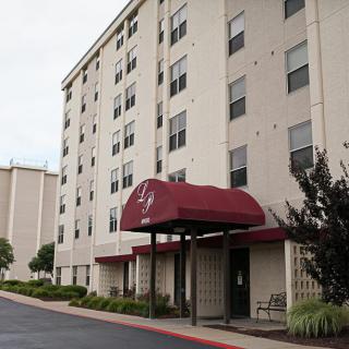 A multi-story hotel building with a red awning over the entrance.
