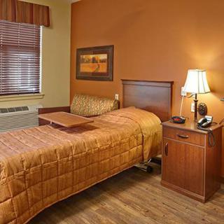 A cozy bedroom with a single bed, nightstand, and warm brown decor.
