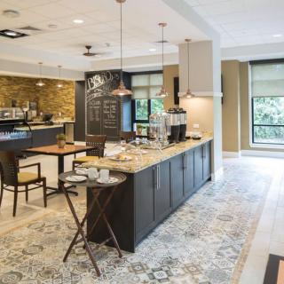 A modern kitchen with a sleek countertop, dining area, and stylish pendant lights.