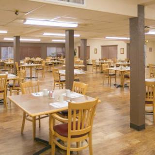 A spacious dining area with wooden tables and chairs, awaiting guests.
