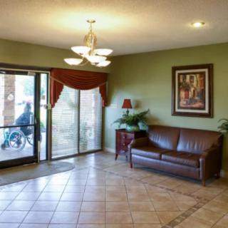 A cozy lobby area with a sofa, lamp, and artwork complemented by tiled flooring and a glass entrance.