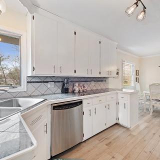 A modern kitchen with white cabinets, stainless steel appliances, and hardwood flooring.