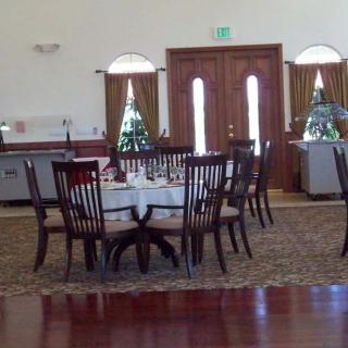 An elegantly set dining area with round tables and wooden chairs inside a restaurant.