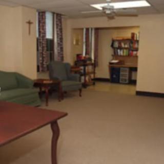 A cozy living room with comfortable seating, a bookshelf, and a carpeted floor.