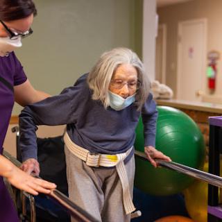 An elderly person receiving assistance during a physical therapy session.