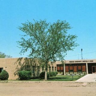 A school building with a tree in front under a clear blue sky.