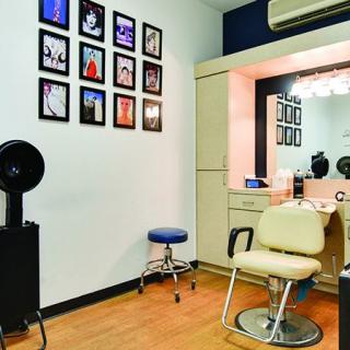 A cozy hair salon interior with styling chair, mirror, and wall decor.