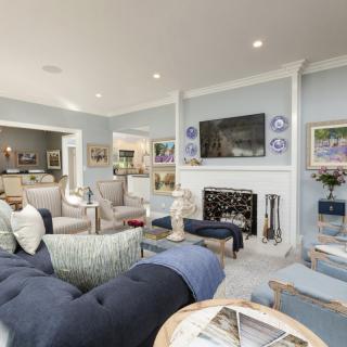 A modern and spacious living room with elegant furnishings, featuring a fireplace and a mounted television.