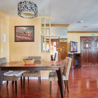 A stylish dining room with a wooden table, chairs, and elegant light fixture, featuring artwork on the wall and a decorative mirror.