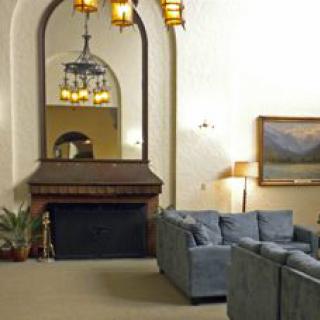 Cozy living room with a large mirror above the fireplace, soft blue sofas, and warm lighting.